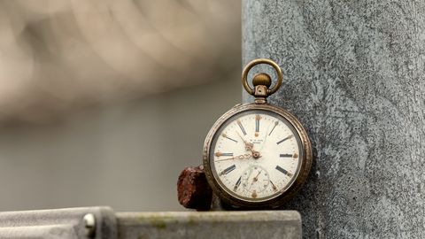 An open pocket watch resting on a stone ledge