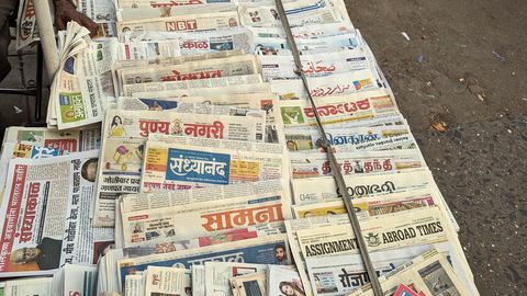A newsstand rack packed with newspapers and magazines