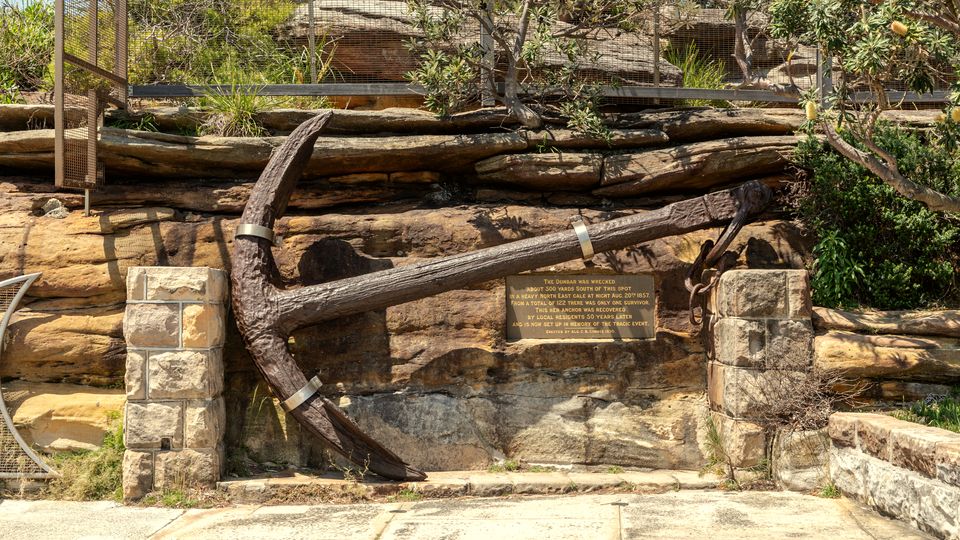 An old iron anchor resting among rocks and roots