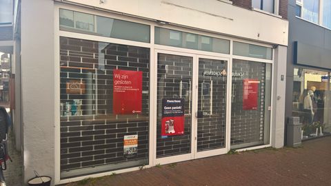 Closed shopfronts with shutters down and notices in the windows