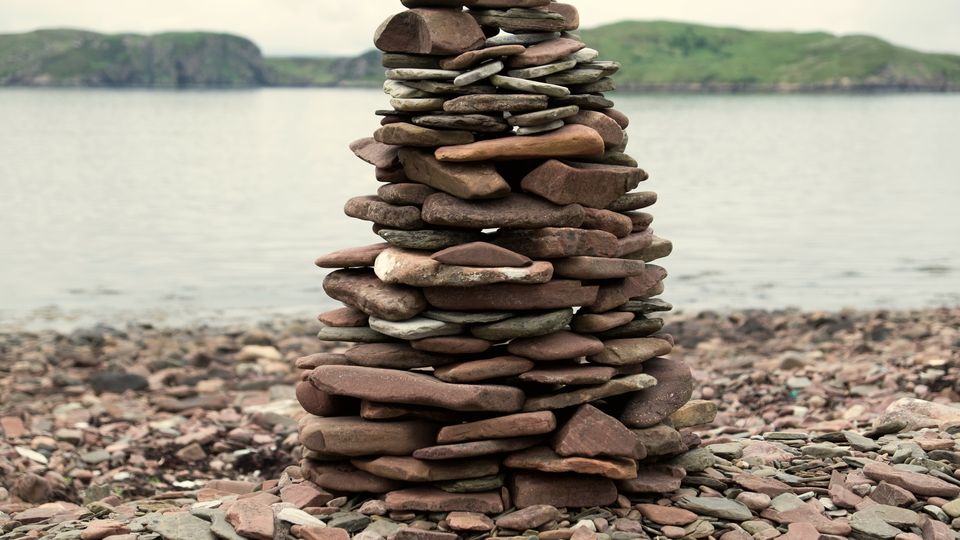 A cairn of balanced flat stones beside the water
