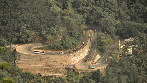 A road winding in hairpin bends down a green mountainside